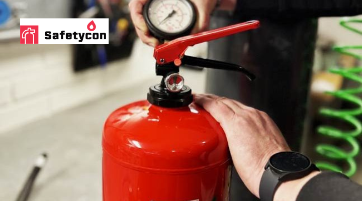 Safetycon-logo, henkilö tarkistaa käsisammutinta